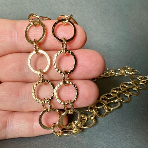 May include: A gold chain necklace with textured, circular links. The chain is made of multiple rows of linked circles.