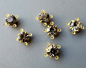 May include: Six gold-toned metal settings with clear, faceted, round rhinestones. Each setting has four loops for attaching to a jewelry piece.