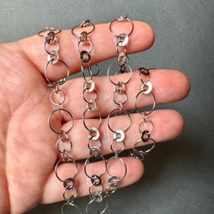 May include: Silver chain necklace with multiple rows of interlocking circles.