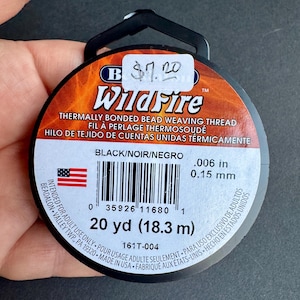 May include: A spool of black beading thread labelled "WildFire" thermally bonded bead weaving thread. The spool is 20 yards (18.3 metres) long and is 0.006 inches (0.15 millimetres) thick.