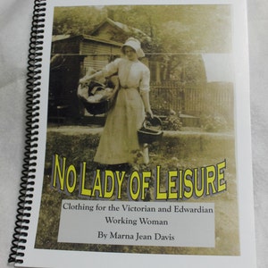 Pode incluir: Uma capa de livro com uma foto vintage de uma mulher com um vestido branco segurando uma cesta. O título do livro é "No Lady of Leisure: Clothing for the Victorian and Edwardian Working Woman" por Marna Jean Davis.