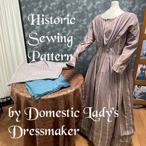 May include: A historic sewing pattern for a dress, with the text "Historic Sewing Pattern by Domestic Lady's Dressmaker" on the table. The dress is a light purple and white striped fabric with a gathered waist. The pattern is on a table with a floral patterned tablecloth.
