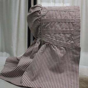 May include: A brown and white gingham bonnet with a gathered ruffle at the crown.