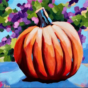 May include: A large orange pumpkin with a deep orange color and a slightly textured surface. The pumpkin is sitting on a light blue background with purple and green flowers.