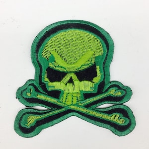 May include: Green embroidered skull and crossbones patch. The skull is green with black eyes and a black outline. The crossbones are green with a black outline.