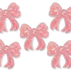 Op de afbeelding: Vijf roze pailletten strikken met een glinsterende afwerking. De strikken zijn ongeveer 5 cm groot en perfect om een ​​toets van glitter toe te voegen aan knutselwerk, kleding of woonaccessoires.