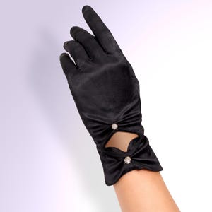 May include: Black satin gloves with a decorative cut-out design. Each glove features a bow detail with a sparkling rhinestone accent. The gloves are a formal accessory, suitable for special occasions.