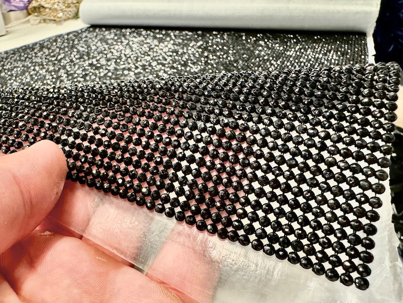 May include: Black rhinestone mesh fabric with a diamond pattern. The mesh is flexible and can be used for a variety of craft projects.