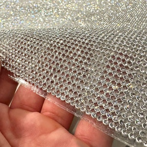 May include: A sheet of clear adhesive-backed rhinestones, arranged in a grid pattern. The rhinestones are small and round, with a clear, iridescent finish.