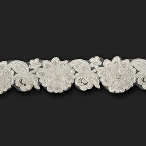 May include: White beaded lace trim with a floral design. The lace is delicate and has a scalloped edge.