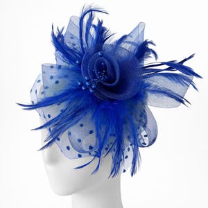 May include: A vibrant blue fascinator featuring a central fabric flower adorned with small beads. The headpiece includes delicate feathers and a sheer, dotted mesh, creating a stylish accessory. This elegant design is suitable for special occasions.