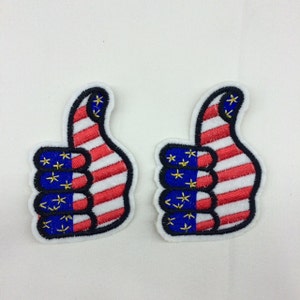 May include: Two iron-on patches with a thumbs up hand design. The hand is in the colors of the American flag, with red and white stripes and blue stars.