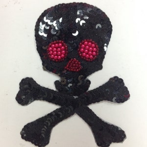 May include: Black skull and crossbones patch made of sequins with red bead eyes.