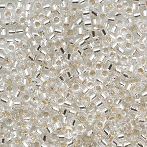 May include: A close-up view of a large quantity of small, clear glass seed beads with silver-colored metallic coating.