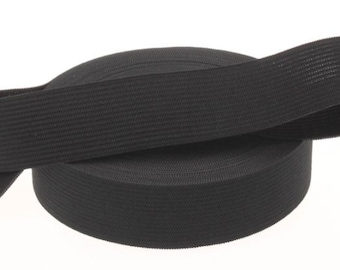 May include: Black elastic band rolled up on a white background. The band is made of a woven material and is approximately 1 inch wide.