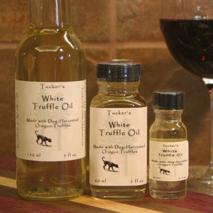 May include: Three glass bottles of white truffle oil, labeled "Tucker's White Truffle Oil", made with dog-harvested Oregon truffles. The bottles are 5 fl oz, 2 fl oz, and 1 fl oz.