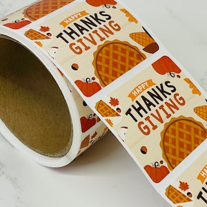 Op de afbeelding: Rol stickers met een Thanksgiving-thema. Elke sticker heeft een taart, pompoenen en herfstbladeren met de tekst "Happy Thanksgiving".
