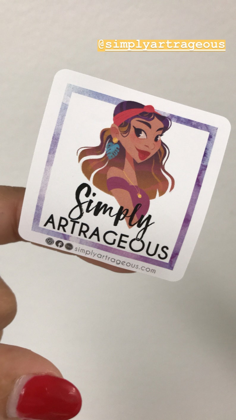 May include: A sticker featuring a cartoon illustration of a woman with brown hair, wearing a red headband, purple shirt, and gold jewellery. The text "Simply Artrageous" is written in black cursive font with the social media handle "@simplyartrageous.com" below.