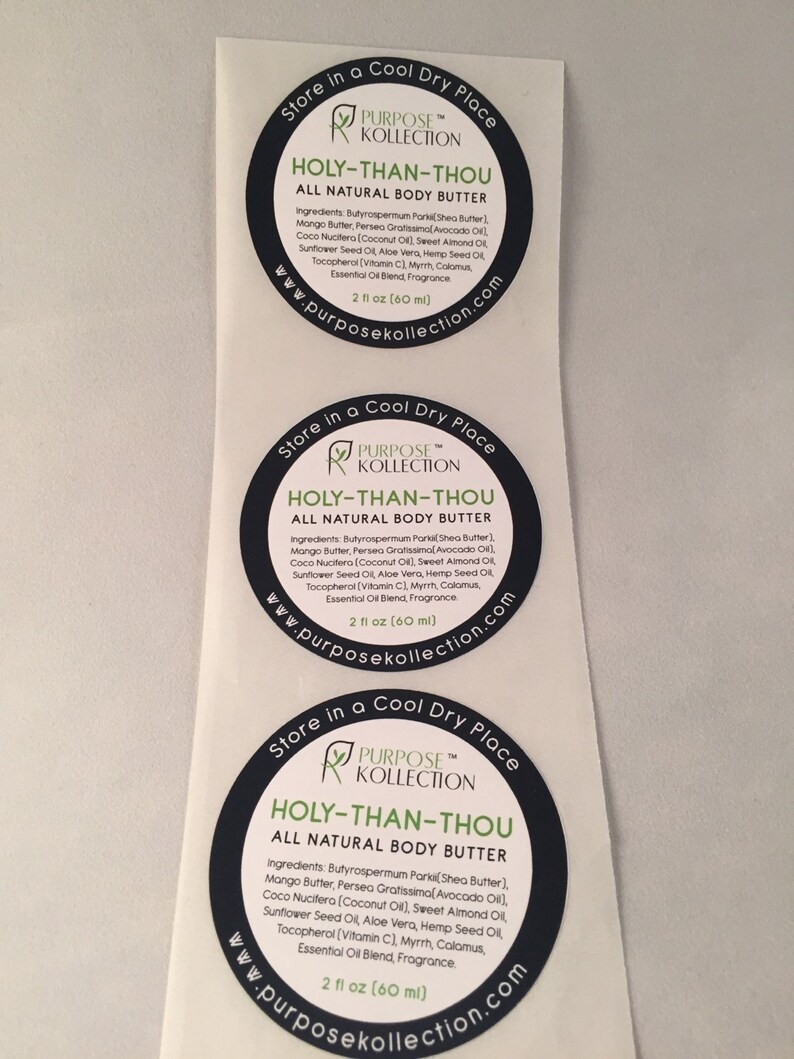 Puede incluir: Tres etiquetas redondas en blanco y negro con el texto "Store in a Cool Dry Place" y "PURPOSE&trade; KOLLECTION" en texto blanco. Las etiquetas tambi&eacute;n tienen el texto "HOLY-THAN-THOU ALL NATURAL BODY BUTTER" en texto blanco. Las etiquetas enumeran los ingredientes de la manteca corporal, que incluyen manteca de karit&eacute;, manteca de mango, aceite de aguacate, aceite de coco, aceite de almendras dulces, aceite de semillas de girasol, aloe vera, aceite de semillas de c&aacute;&ntilde;amo, tocoferol, mirra, c&aacute;lamo, mezcla de aceites esenciales y fragancia. Las etiquetas tambi&eacute;n indican que la manteca corporal es de 2 fl oz (60 ml).