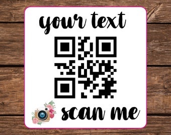 May include: White square sticker with a black and white QR code, a camera icon with pink flowers, and the text "your text" and "scan me" in black cursive font.