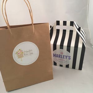 May include: A brown paper bag with a white circle sticker that says "Prettycakes Bake Shop" and a black and white striped box with a white circle sticker that says "Marley's Treats".