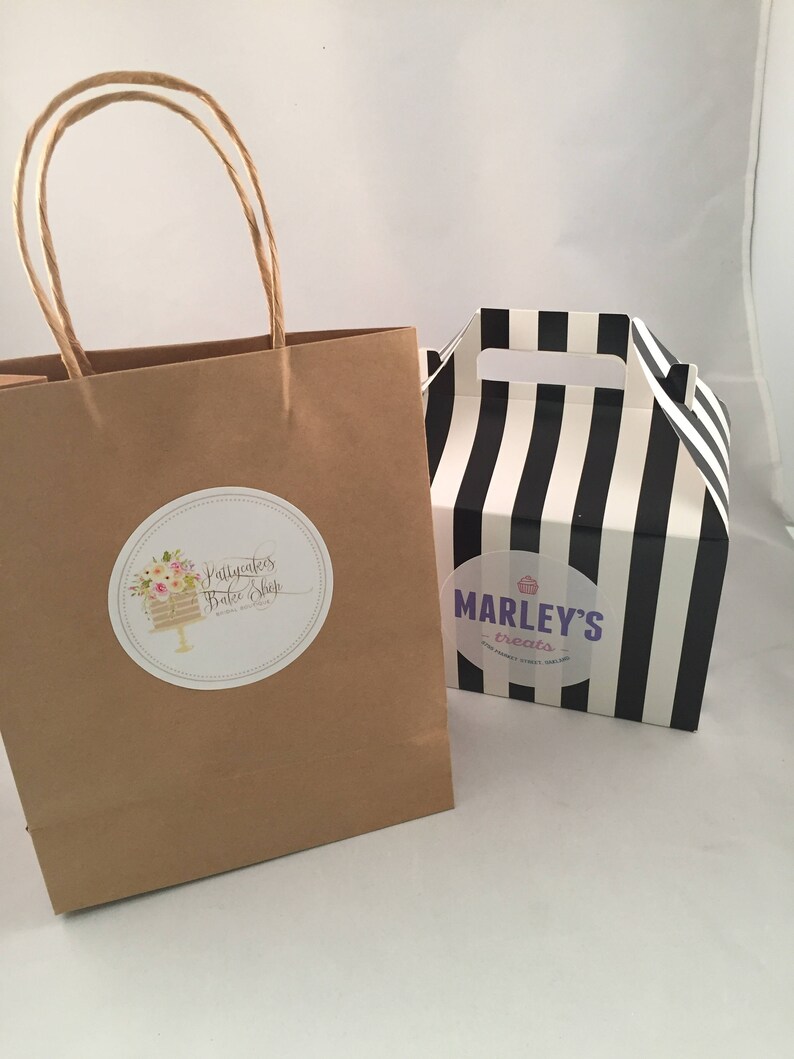 May include: A brown paper bag with a white circle sticker that says "Prettycakes Bake Shop" and a black and white striped box with a white circle sticker that says "Marley's Treats".