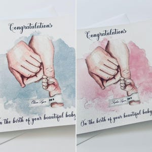 Puede incluir: Dos tarjetas de felicitación con una ilustración en acuarela de una mano adulta sosteniendo la mano de un bebé. Las tarjetas muestran el texto Congratulations y On the birth of your beautiful baby. Una tiene un fondo azul y la otra rosa.