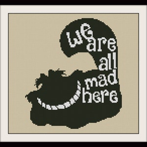 May include: Cross-stitch art in a black frame. The design features a dark green silhouette with the text "We are all mad here" in white. The background is a light beige colour.