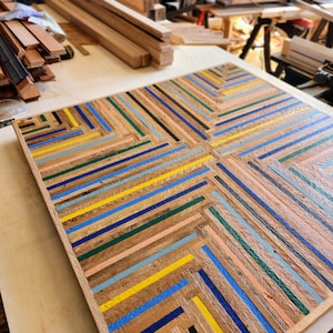 Top view of reclaimed wood table top in colorful geometric stripe pattern. Shown on work table in artis's woodshop.