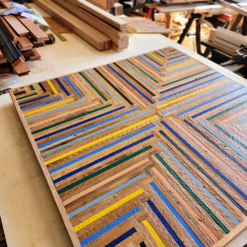 Top view of reclaimed wood table top in colorful geometric stripe pattern. Shown on work table in artis's woodshop.