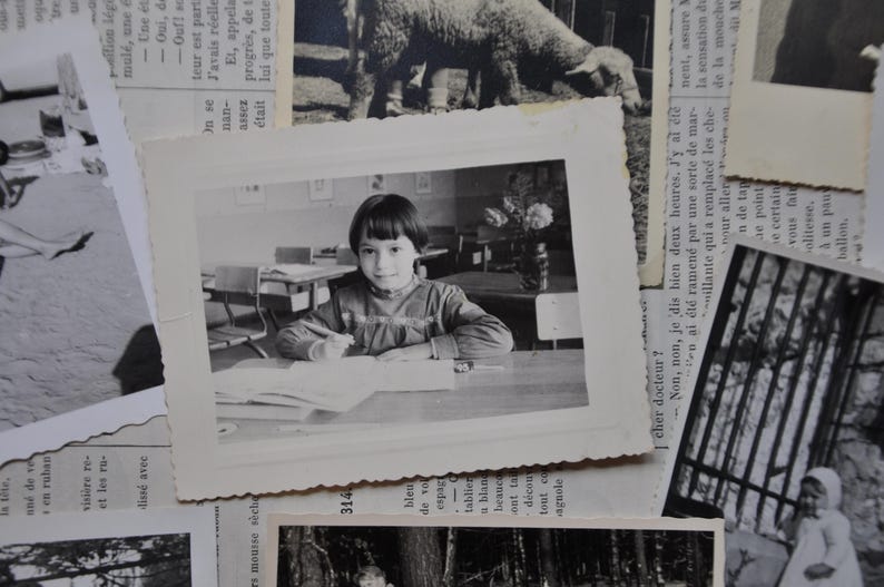 Puede incluir: Foto en blanco y negro de una ni&ntilde;a sentada en un escritorio en un aula. Lleva una camisa de color claro y tiene el pelo recogido hacia atr&aacute;s. Est&aacute; mirando un libro delante de ella.