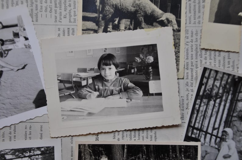 Puede incluir: Una fotograf&iacute;a en blanco y negro de una ni&ntilde;a sentada en un escritorio en un aula. Lleva una camisa de color claro y tiene el pelo recogido hacia atr&aacute;s. Est&aacute; mirando un libro delante de ella.