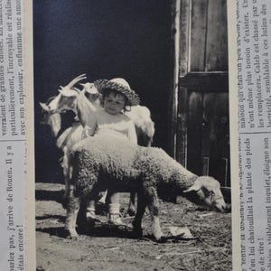 Puede incluir: Una ni&ntilde;a peque&ntilde;a con un sombrero de paja est&aacute; de pie entre dos cabras y una oveja. La ni&ntilde;a lleva un vestido blanco y sonr&iacute;e. Las cabras y la oveja est&aacute;n mirando a la c&aacute;mara.