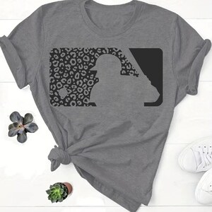 May include: A gray t-shirt with a black and white leopard print baseball logo. The logo is a silhouette of a baseball player in a batting stance.