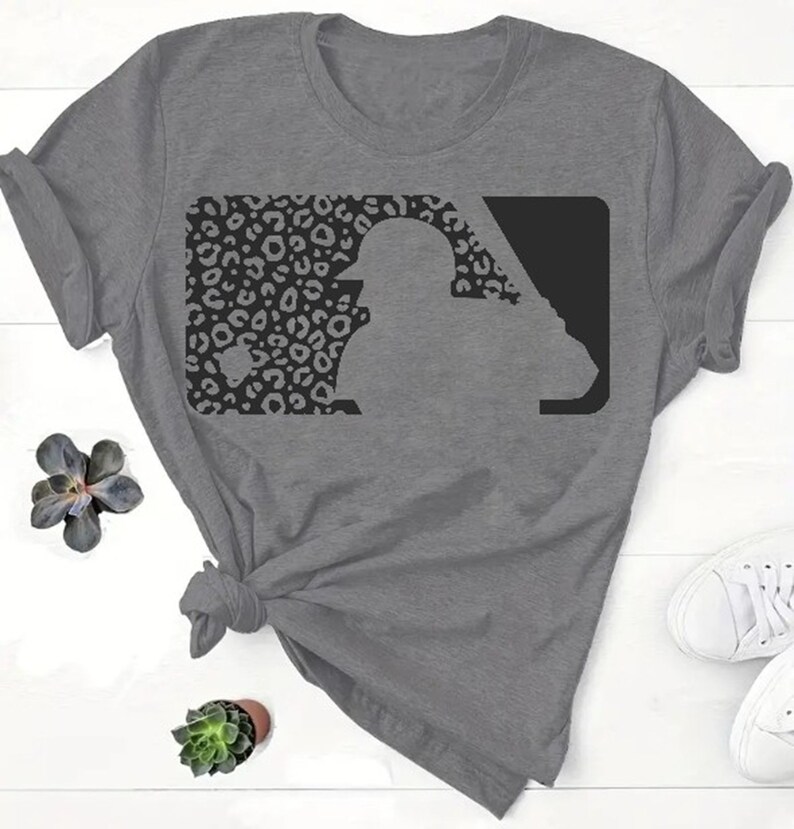 May include: A gray t-shirt with a black and white leopard print baseball logo. The logo is a silhouette of a baseball player in a batting stance.