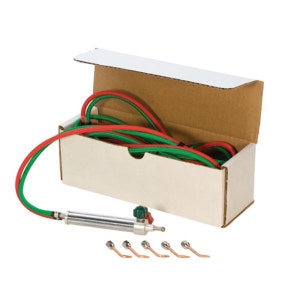May include: A silver soldering torch with a green and red hose and five different sized tips in a white cardboard box.