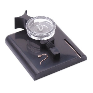 May include: A black plastic jewelry making tool with a clear plastic rotating disc, a small metal hook, and a groove for wire.