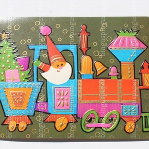 May include: A colorful Christmas card featuring a whimsical train with Santa Claus waving from the engine. The train is decorated with a Christmas tree, gifts, and various festive elements in shades of blue, orange, pink, and green. The background is olive green with gold circles.