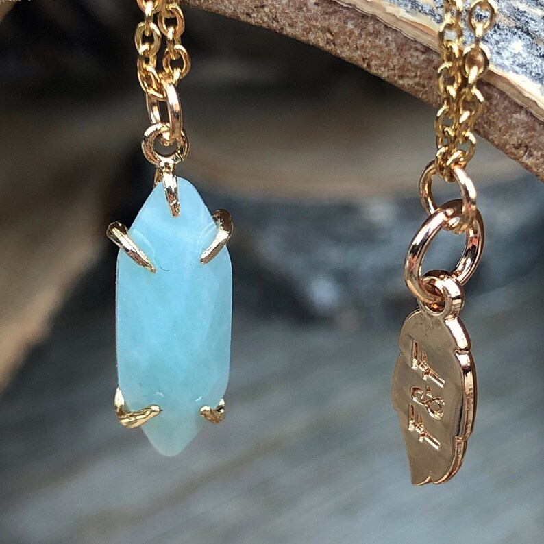 May include: A gold chain necklace with a light blue gemstone pendant and a gold charm with the text "F21" on it.