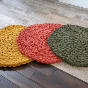 Pu&ograve; includere: Tre cuscini rotondi in crochet per il pavimento in giallo senape, arancio corallo e verde oliva.