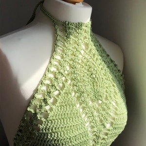 Puede incluir: Un top halter de crochet de color verde claro con un delicado diseño calado.
