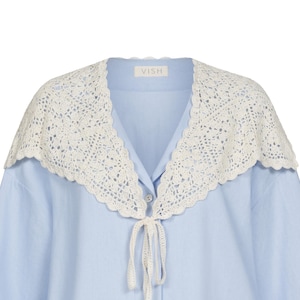 Peut inclure: Chemise bleu clair avec un col en crochet blanc. Le col est orn&eacute; d'une bordure festonn&eacute;e et d'une fermeture &agrave; nouer. La chemise porte la marque "VISH" sur le col.