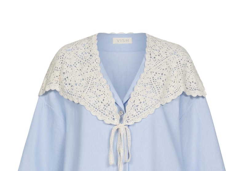 Peut inclure: Chemise bleu clair avec un col en crochet blanc. Le col est orn&eacute; d'une bordure festonn&eacute;e et d'une fermeture &agrave; nouer. La chemise porte la marque "VISH" sur le col.