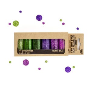 May include: A glitter set in a cardboard box with the text "Glitter Set" and "Mardi Gras". The set includes six glitter tubes in shades of green, purple, and pink. Scattered around the box are green and purple glitter dots.