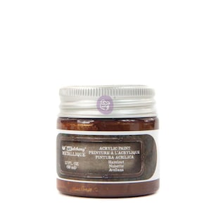 May include: A 1.7 fluid ounce jar of metallic acrylic paint in the color Hazelnut. The jar is labeled with the brand name "Art Alchemy" and the paint color name in English, French, and Spanish.