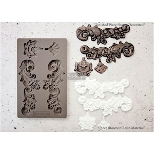 May include: A silicone mold for creating decorative resin pieces. The mold features two large, ornate designs and three smaller, detailed designs. The image also shows examples of finished resin pieces in both white and brown.