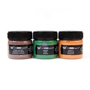 May include: Three small jars of acrylic paint in dark brown, green, and rusty orange. The jars are labeled with the brand name "art extravaganza" and the color names in English, French, and Spanish.