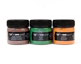 May include: Three small jars of acrylic paint in dark brown, green, and rusty orange. The jars are labeled with the brand name "art extravaganza" and the color names in English, French, and Spanish.