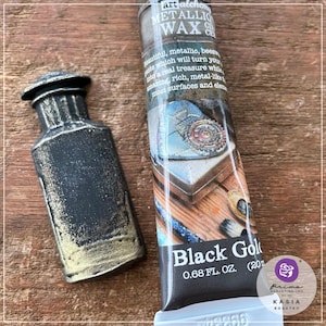 May include: A tube of black gold metallic wax with a gold and black bottle in the background. The tube is labeled "Black Gold" and "0.68 FL. OZ. (20 ml)".