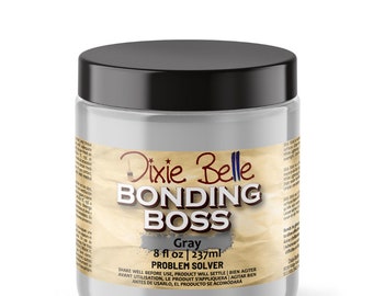 May include: A gray Dixie Belle Bonding Boss Problem Solver in a clear jar with a black lid. The jar is labeled with the product name, color, and size: 8 fl oz | 237ml. The label also includes instructions to shake well before use, as the product will settle.